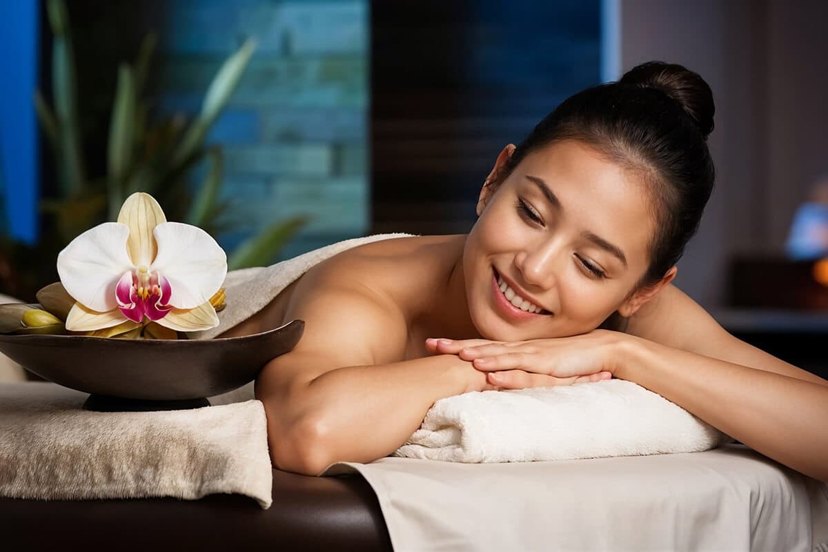 Guest smiling during an evening massage beside an orchid